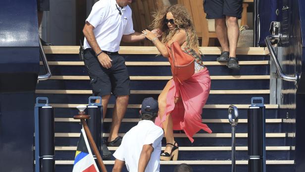 Mariah Carey verlässt eine Yacht mit Hilfe eines Sicherheitsmannes.