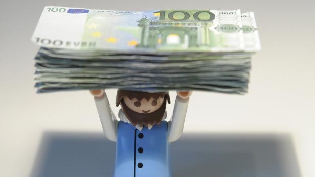Eine Playmobilfigur trägt einen Stapel von 100-Euro-Scheinen.