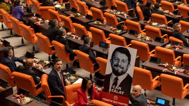 Abgeordnete im türkischen Parlament mit einem Bild von Oppositionspolitiker Can Atalay.