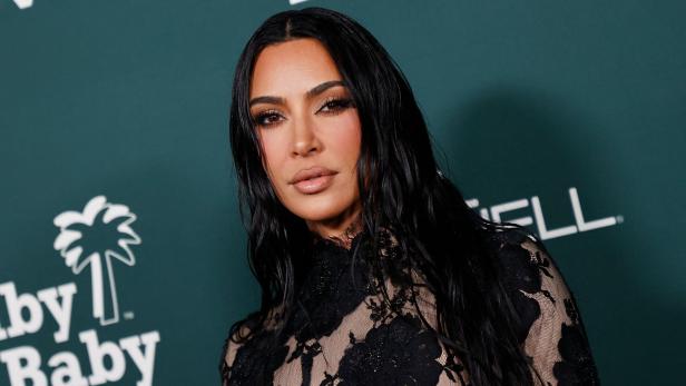 Kim Kardashian posiert auf einem Event mit einem schwarzen Spitzenkleid.