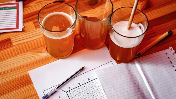 Drei Gläser mit Getränken und ein Pubquiz-Bogen auf einem Tisch.