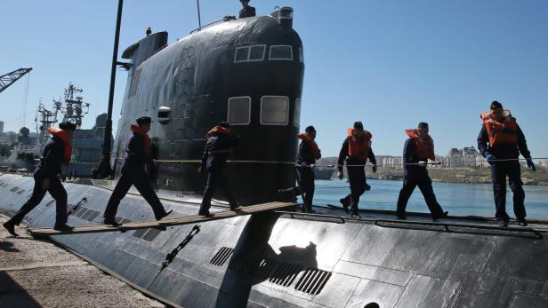 Marinepersonal überquert ein U-Boot mit Hilfe eines Holzstegs.