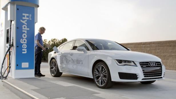 Ein Mann betankt einen weißen Audi A7 h-tron an einer Wasserstofftankstelle.