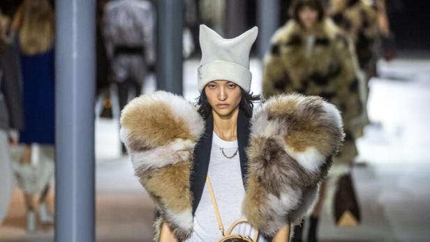 Ein Model posiert für Louis Vuitton in einem Pelzkragen und einer eiförmigen Handtasche.