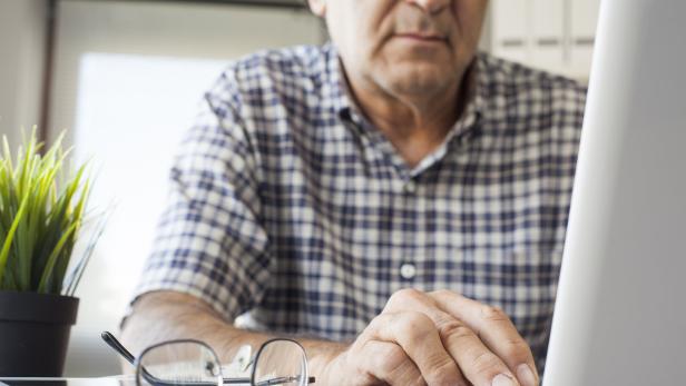 Ein älterer Mann tippt am Laptop.