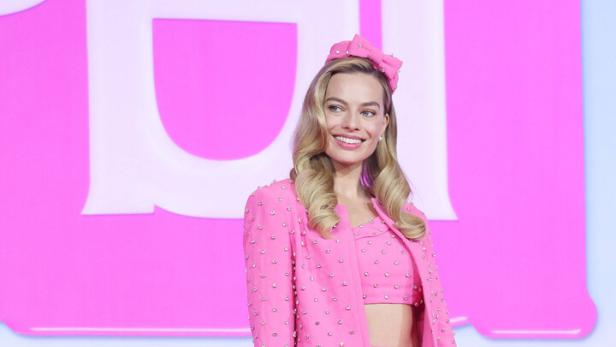 Margot Robbie in einem pinkfarbenen Ensemble mit einer herzförmigen Handtasche.