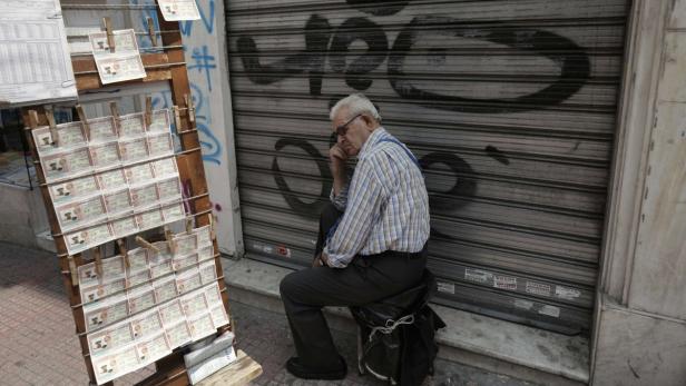 A lottery ticket vendor sits outside of a closed shop in central Athens June 28, 2013. Greece&#039;s privatisations agency (TAIPED) on Tuesday urged a consortium led by betting monopoly OPAP to sign a deal to sell its state lotteries, paving the way for completion of the privatisation of OPAP, the country&#039;s first major asset sale under its foreign bailout. REUTERS/John Kolesidis (GREECE - Tags: POLITICS BUSINESS)