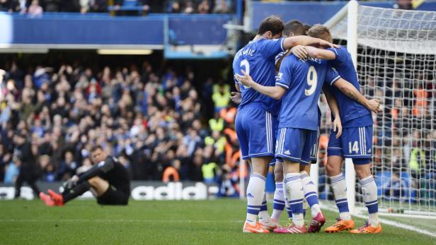 Chelsea-Spieler umarmen sich auf dem Spielfeld, während ein Torwart im Hintergrund sitzt.
