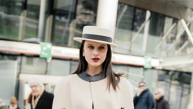 Ein Model mit Hut und Cape auf der Fashion Week.