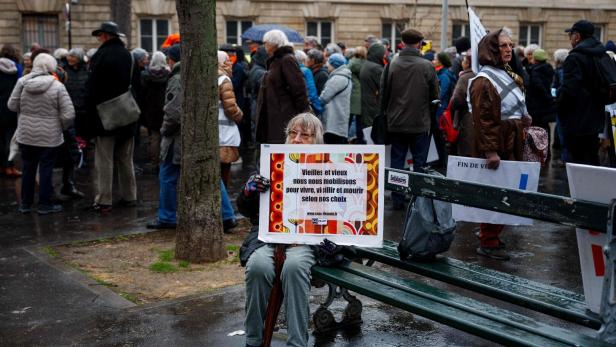 Eine Frau hält ein Plakat mit der Aufschrift "Alte Frauen, alte Männer, wir versammeln uns, um zu leben, alt zu werden und zu sterben, wie wir es wollen" in Paris am 23. Januar 2024.