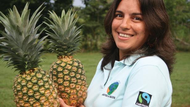 Eine lächelnde Frau hält zwei Ananas in ihren Händen.
