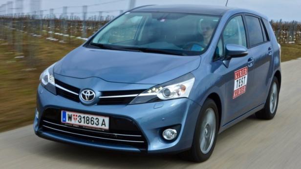 Ein blauer Toyota Verso fährt auf einer Landstraße an einem Weinberg vorbei.