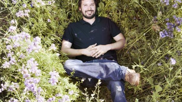 Ein Mann liegt in einem Feld mit lila blühenden Pflanzen.