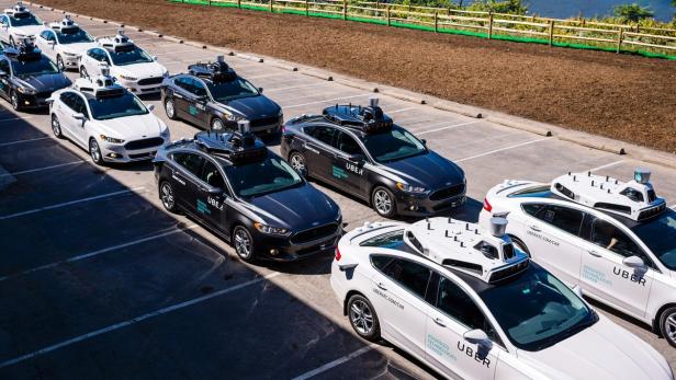 Eine Reihe von selbstfahrenden Uber-Autos parkt auf einem Parkplatz.
