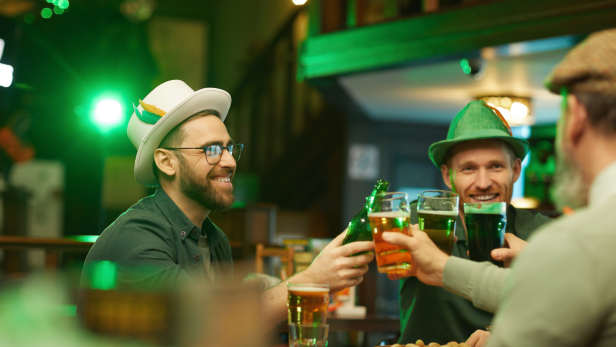 Drei Freunde stoßen in einer Bar mit Bier auf den St. Patrick's Day an.