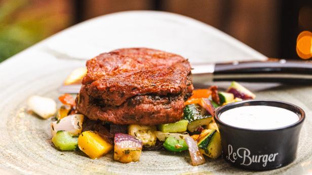 Ein „Le Burger“-Gericht mit Gemüse und einem Dip wird serviert.