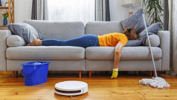 Erschöpfte Person liegt nach dem Putzen auf der Couch.