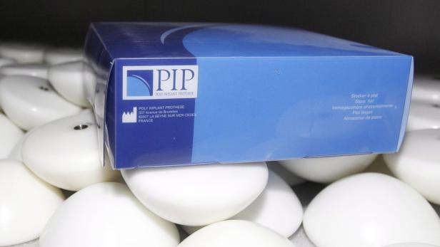 Eine blaue Verpackung von PIP Poly Implant Prothese liegt auf mehreren Brustimplantaten.