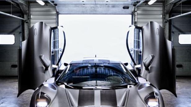 Ein grauer Jaguar CX-75 mit geöffneten Flügeltüren steht in einer Garage.