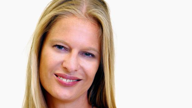 Eine lächelnde Frau mit blonden Haaren vor einem weißen Hintergrund.