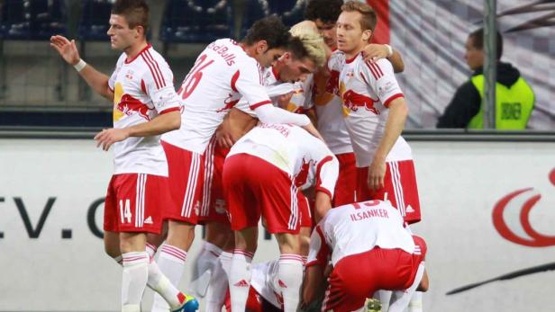 Eine Gruppe Fußballspieler in rot-weißen Trikots umarmt sich auf dem Spielfeld.
