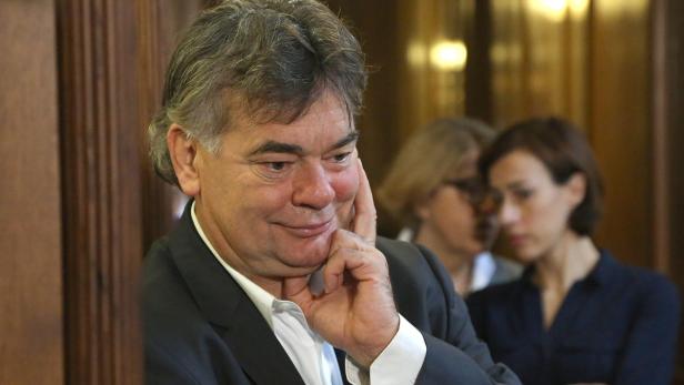 Ein Mann mit grauem Haar stützt sein Gesicht mit der Hand.