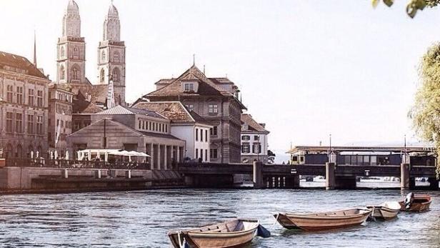 Blick auf den Fluss Limmat in Zürich mit dem Grossmünster im Hintergrund.