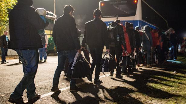 Flüchtlinge gehen am 30. Oktober an der deutsch-österreichischen Grenze nahe Wegscheid (Bayern) zu einem Bus der Bundespolizei, der sie über die Grenz bringt.