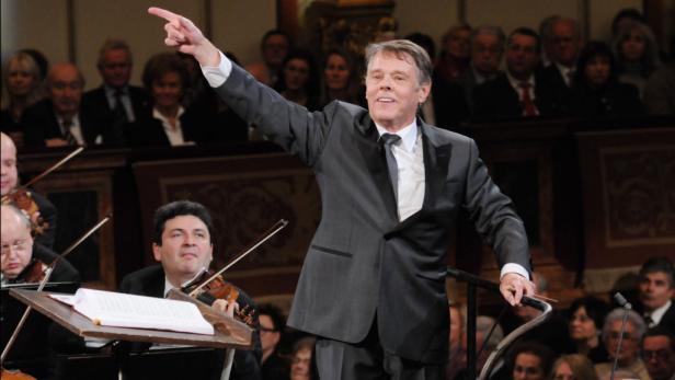 Ein Dirigent leitet ein Orchester mit erhobenem Zeigefinger.
