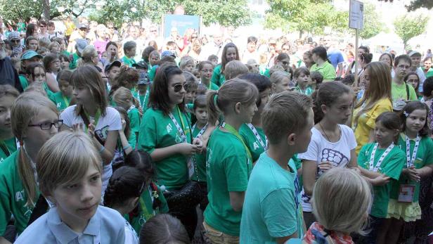 Eine große Gruppe von Kindern und Erwachsenen versammelt sich im Freien.
