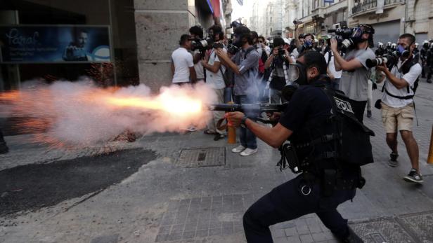 epa03780978 A Turkish riot police officer fires tear gas to disperse protestors during an anti-government protest near Taksim Square in Istanbul, Turkey, 08 July 2013. Turkish protestors tried to gather at Gezi Park, which has been the source of protests since 31 May in Istanbul and many other cities across Turkey, after it opened to the public on 08 July. EPA/SEDAT SUNA