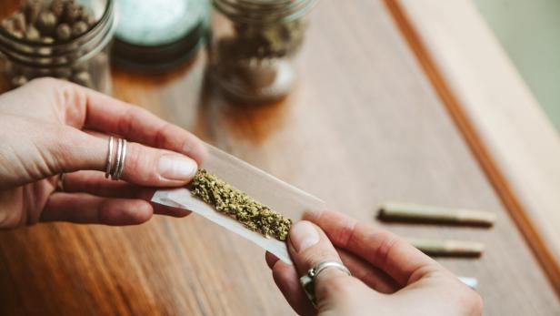 Hands making cannabis joint at marijuana shop