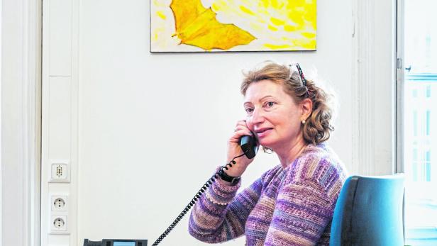 Eine Frau sitzt an einem Schreibtisch und telefoniert.