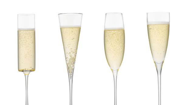Vier verschiedene Sektgläser gefüllt mit sprudelndem Sekt.