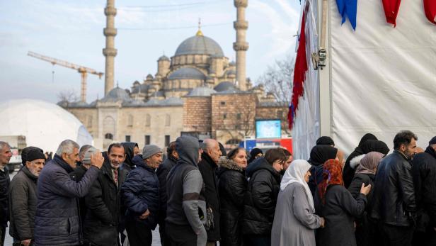 Gläubige stehen am 15. März 2024 auf dem Eminonu-Platz in Istanbul Schlangefür das Iftar-Essen.