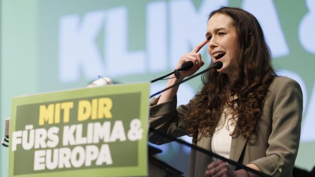 Grüne Spitzenkandidatin für EU-Wahl 2024 Lena Schilling deutet sich mit dem Finger an den Kopf bei einer Rede.