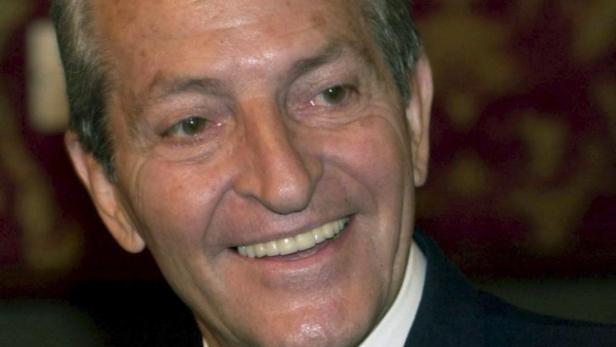 Ein lächelnder älterer Mann mit Anzug.