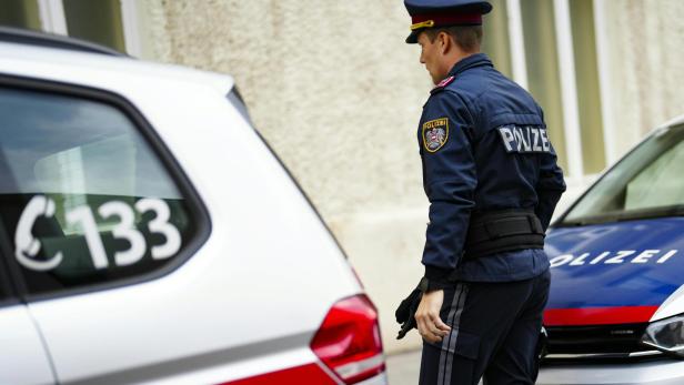 Symbolbild Polizeiauto: Polizist geht zwischen 2 Polizeiautos durch
