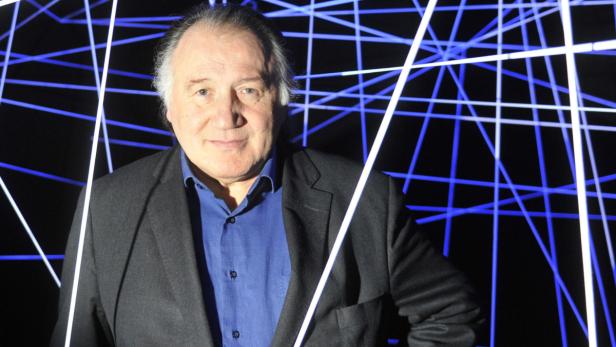 Ein Mann in einem Anzug steht vor einem Hintergrund aus blauen Linien.