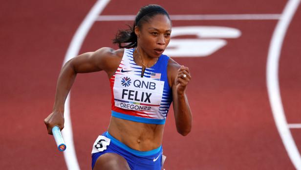 Allyson Felix läuft mit einem Staffelstab auf einer roten Laufbahn.