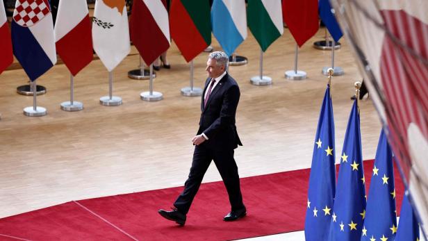 Karl Nehammer schreitet beim EU-Gipfel über einen roten Teppich. Flaggen der EU-Länder stehen im Hintergrund