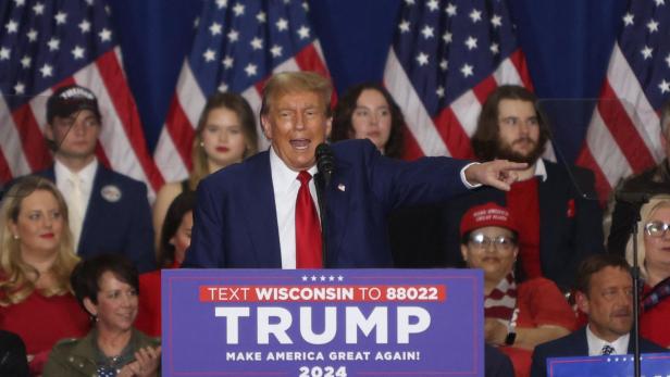 Trump deutet mit dem Finger in die Menge bei einem Wahlkampauftritt in Wisconsin. Hinter ihm klatschen Menschen.