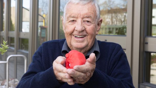 Der Patient Walter Weiss hält ein Herzmodell in der Hand.