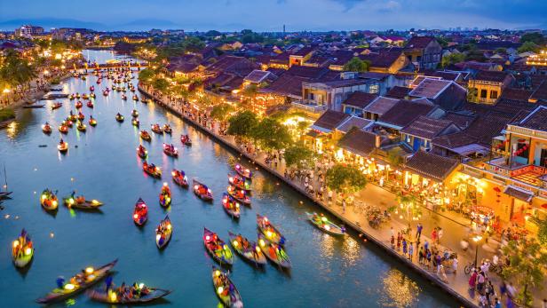 Blick auf das abendliche Hoi An in Vietnam mit beleuchteten Booten auf dem Fluss.