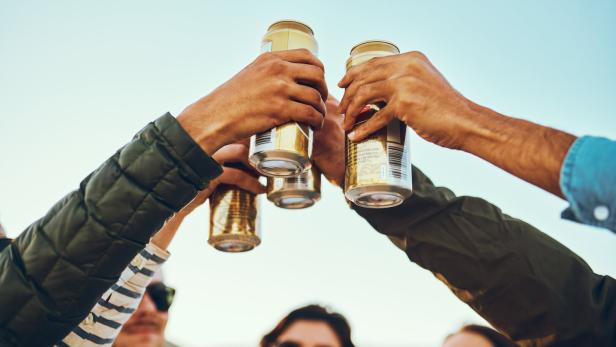 Eine Gruppe von Freunden stößt mit Bierdosen an.