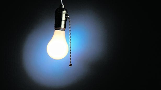 Single lit light bulb on a chain on a black background