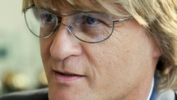 Ein Mann mit blonden Haaren und Brille trägt ein blaues Jackett.
