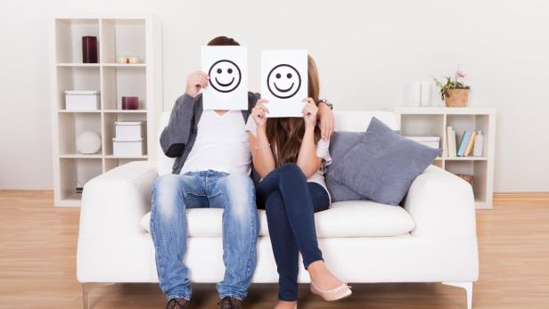 Couple covered faces with smiley white paper. Bildnummer: 47109428 Fröhlichkeit ausspannend bedeckt board bodenbelag deckung entspannt entwerfen frau freudig furnishings gesicht hausrat hold holding holz interior jung karte kissen konzept lebensstil leute living lounge lächeln lässig mann modern paar papier sauber settee simplicity smiley sofa symbol verstecken weiß zeichen zimmerer zuhause