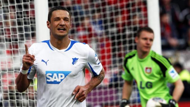 Ein Fußballspieler jubelt mit erhobenem Zeigefinger, während ein Torwart im Hintergrund steht.