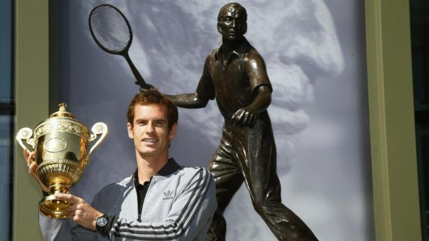 Tennis player Andy Murray of Britain holds the trophy under a statue of former British champion Fred Perry, at Wimbledon, southwest London July 8, 2013. Murray wiped out 77 years of pain when he became the first British man since 1936 to win the men&#039;s title at Wimbledon with a stunning 6-4 7-5 6-4 victory over world number one Novak Djokovic on Sunday. REUTERS/Chris Helgren (BRITAIN - Tags: SPORT TENNIS TPX IMAGES OF THE DAY)